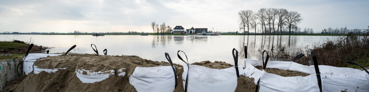 Zandzakken vanwege hoogwater in de Rijn tussen Ingen en Elst met op de achtergrond een huis, in februari 2021.