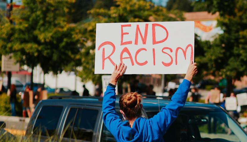 Foto van vrouw in protest met bord: 'End Racism'